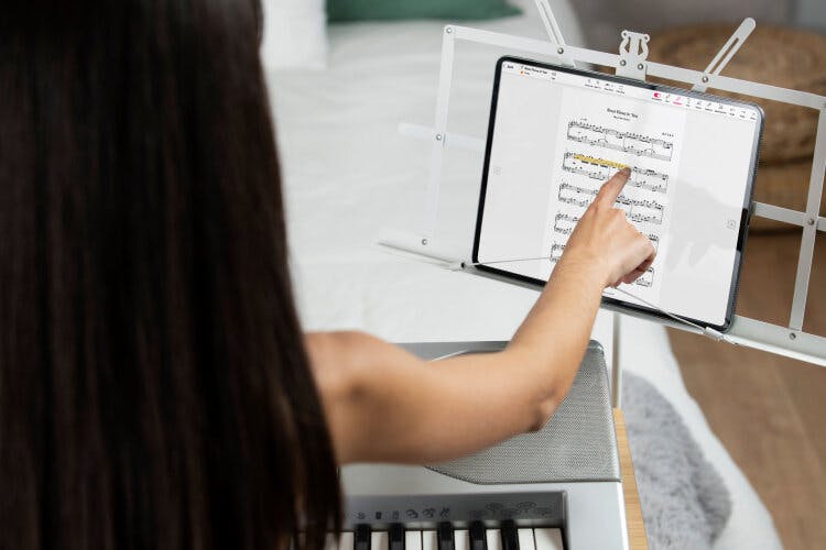 Someone playing the piano with a digital sheet music stand