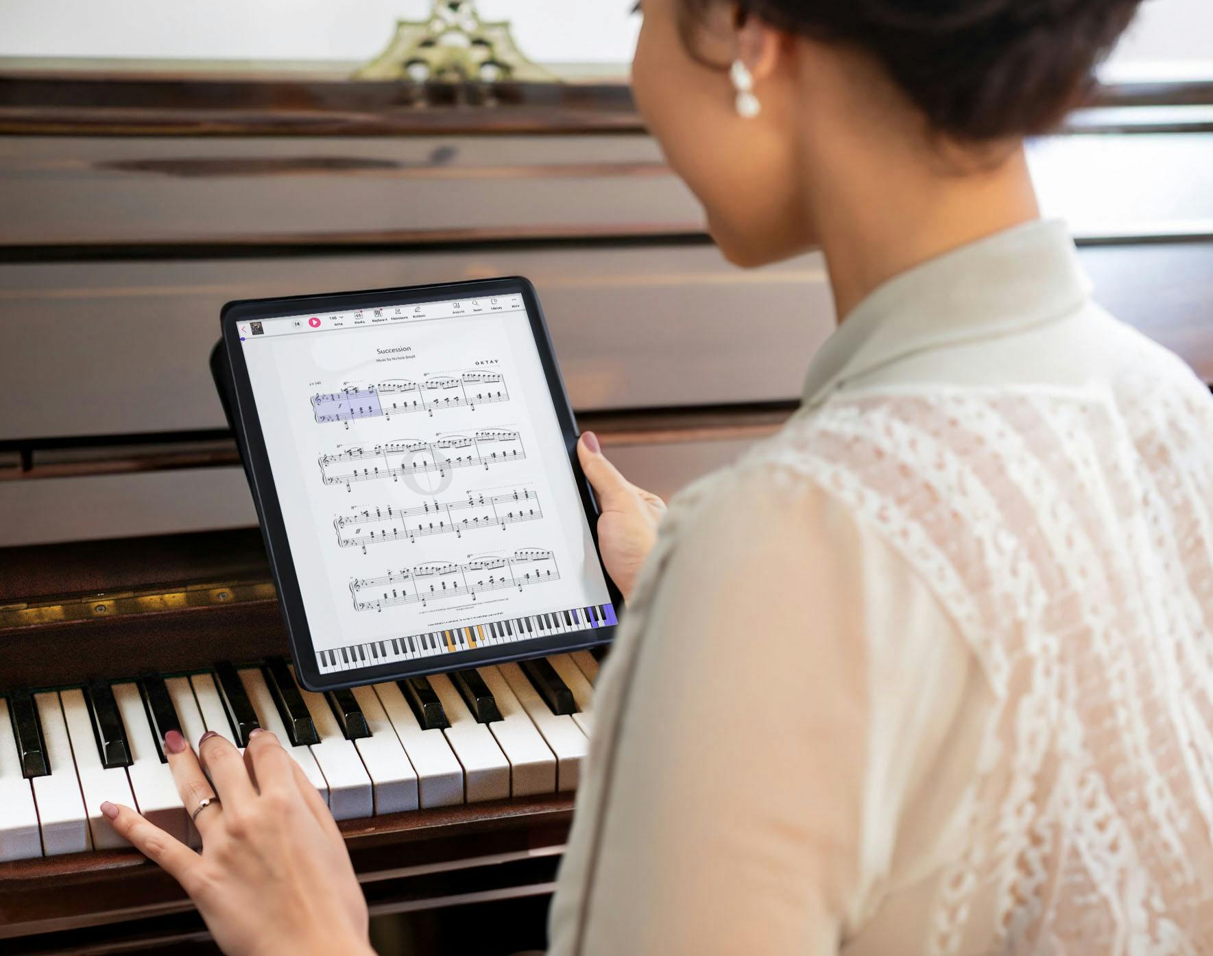 Woman sitting at the piano holding a tablet